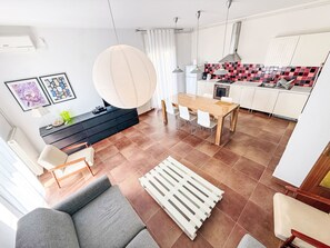 A modern kitchen with a checkered backsplash, a dining area with a wooden table and chairs, and a living area with a sofa and a coffee table. - LacoDeLama mini resort - Wohnung Marta mit Pool by Interhome (Medulin/Ližnjan)