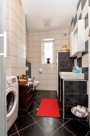 A compact kitchen with a washing machine, a sink, and a window.