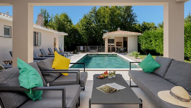 A modern outdoor living area with a pool, seating, and a small building with a tiled roof. - Villa Lejla by Interhome (Drenje)