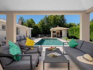 Ein moderner Außenbereich mit Pool, Sitzgelegenheiten und einem kleinen Gebäude mit einem gepflasterten Dach.