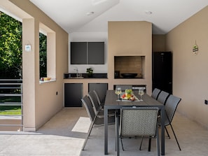 Eine moderne Küche mit Essbereich, ausgestattet mit Backofen, Spüle und einem schwarzen Kühlschrank.