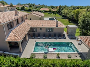 Ein Haus mit Swimmingpool, Schwane als Schwimmfigur und einem Garten.