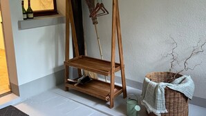 A wooden shelf with a broom and clothes hanger, a wicker basket, and bottles by a window. - Historisches Anwesen - zeitloser Charme und moderner Luxus by Interhome (Ennenda)