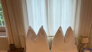 A neatly made bed with white bedding and a beige throw blanket, a bedside table with a lamp, and a window with sheer curtains. - Historisches Anwesen - zeitloser Charme und moderner Luxus by Interhome (Ennenda)