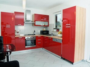 A modern kitchen with red cabinets, a microwave, a stove, and a sink. - 'Villa Grguci' mit eigener Terrasse by Interhome (Rovinj/Kanfanar)