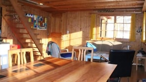 A wooden interior with a dining table, chairs, a sofa, and a staircase. - Weissenberge Gfell by Interhome (Matt)