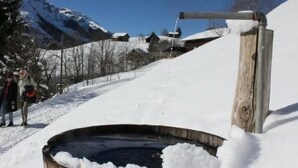 A wooden structure with a metal pipe, surrounded by snow and a clear sky. - Weissenberge Gfell by Interhome (Matt)