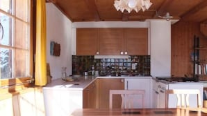 A kitchen with wooden cabinets, a countertop, and a window with yellow curtains. - Weissenberge Gfell by Interhome (Matt)