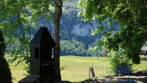 Un'area salotto esterna rustica con una panchina in pietra, una sedia in metallo e un piccolo tavolo.