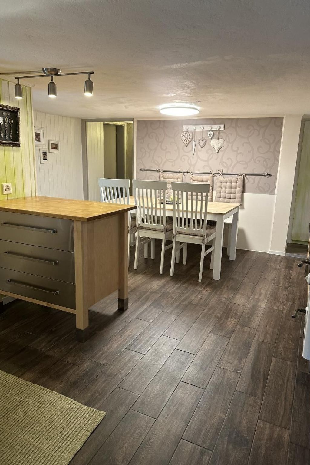 A kitchen with a wooden countertop, white chairs, and a dining table.