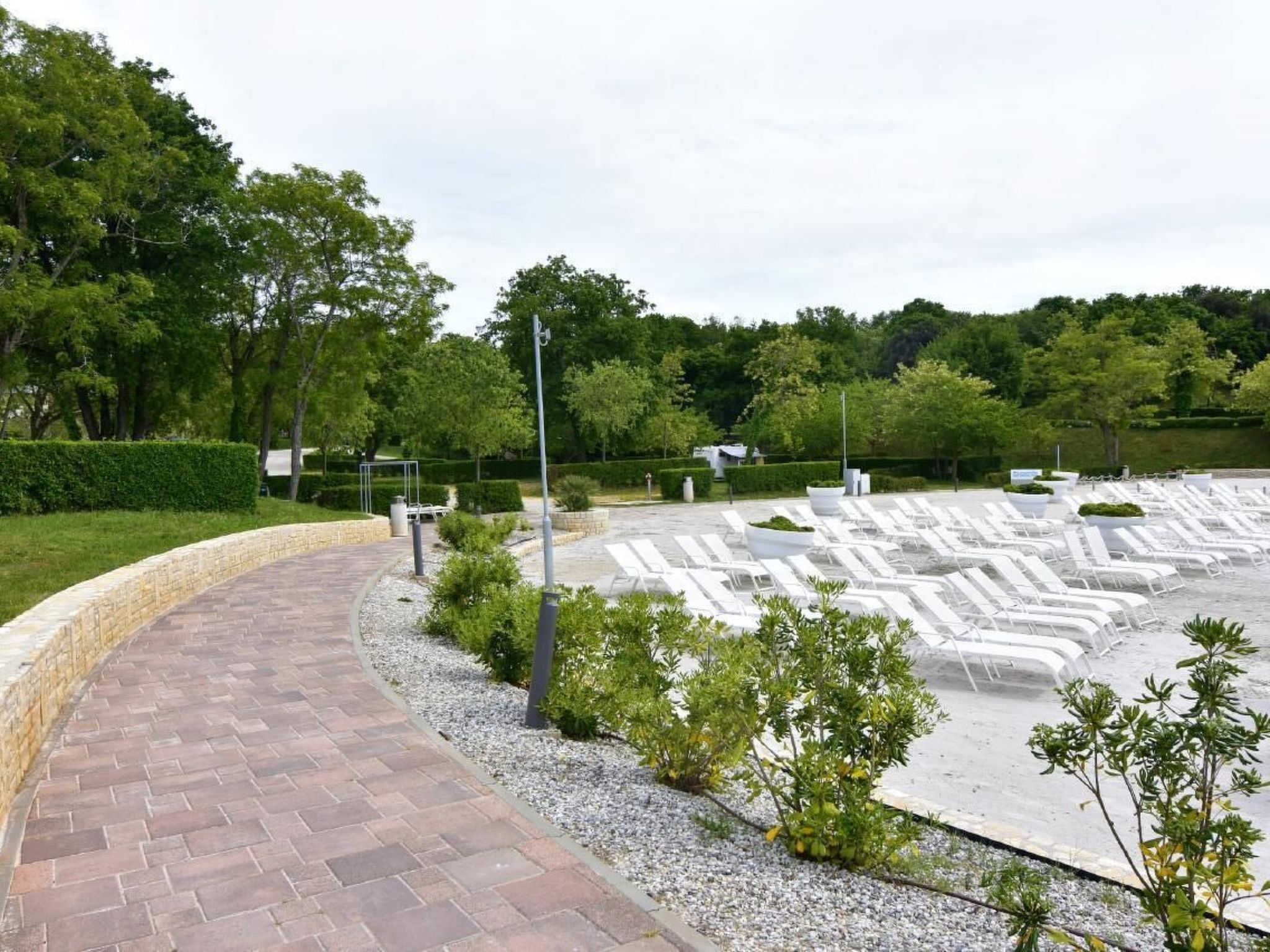 A landscaped area with a paved walkway, seating areas, and greenery.