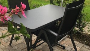 En uteplats med ett bord och stolar, omgiven av grönska och träd.