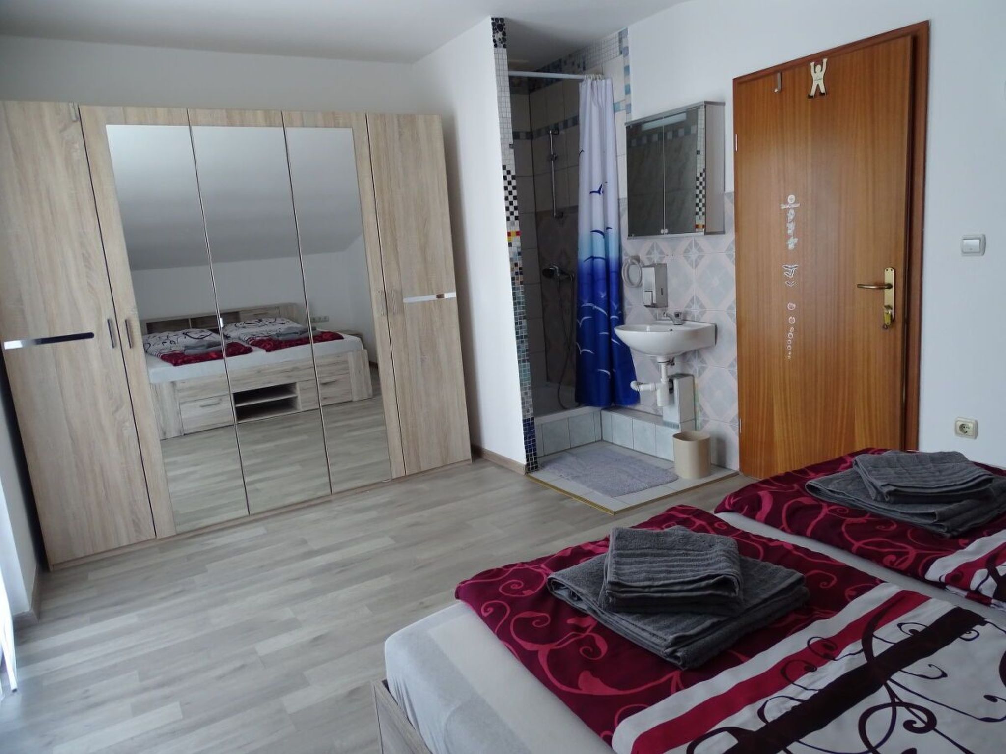 Quarto com cama, armário, chuveiro e pia.