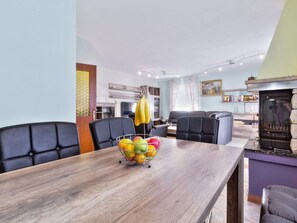 Ein moderner Essbereich mit einem Holztisch, schwarzen Ledersesseln und einer Obstschale.