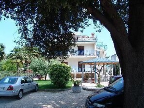 A hotel with a two-story building, a covered outdoor seating area, and a parking lot with cars. - mit Blick auf das Wasser by Interhome (Umag)