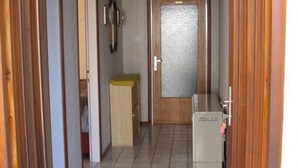 Ein Flur mit Holztüren, Fliesenboden und einem kleinen Schrank.