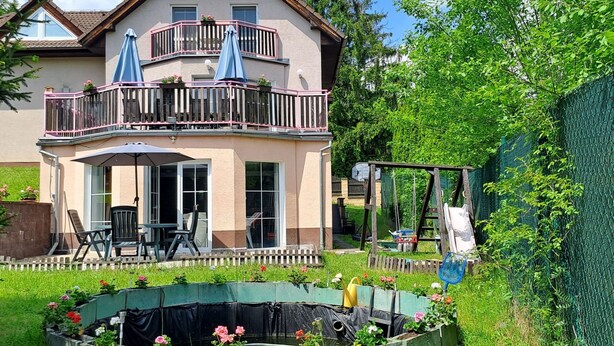 A two-story house with a balcony, a covered patio, and a garden with raised flower beds. - Wellness Villa near Prague - all inclusive by Interhome (Vranov)