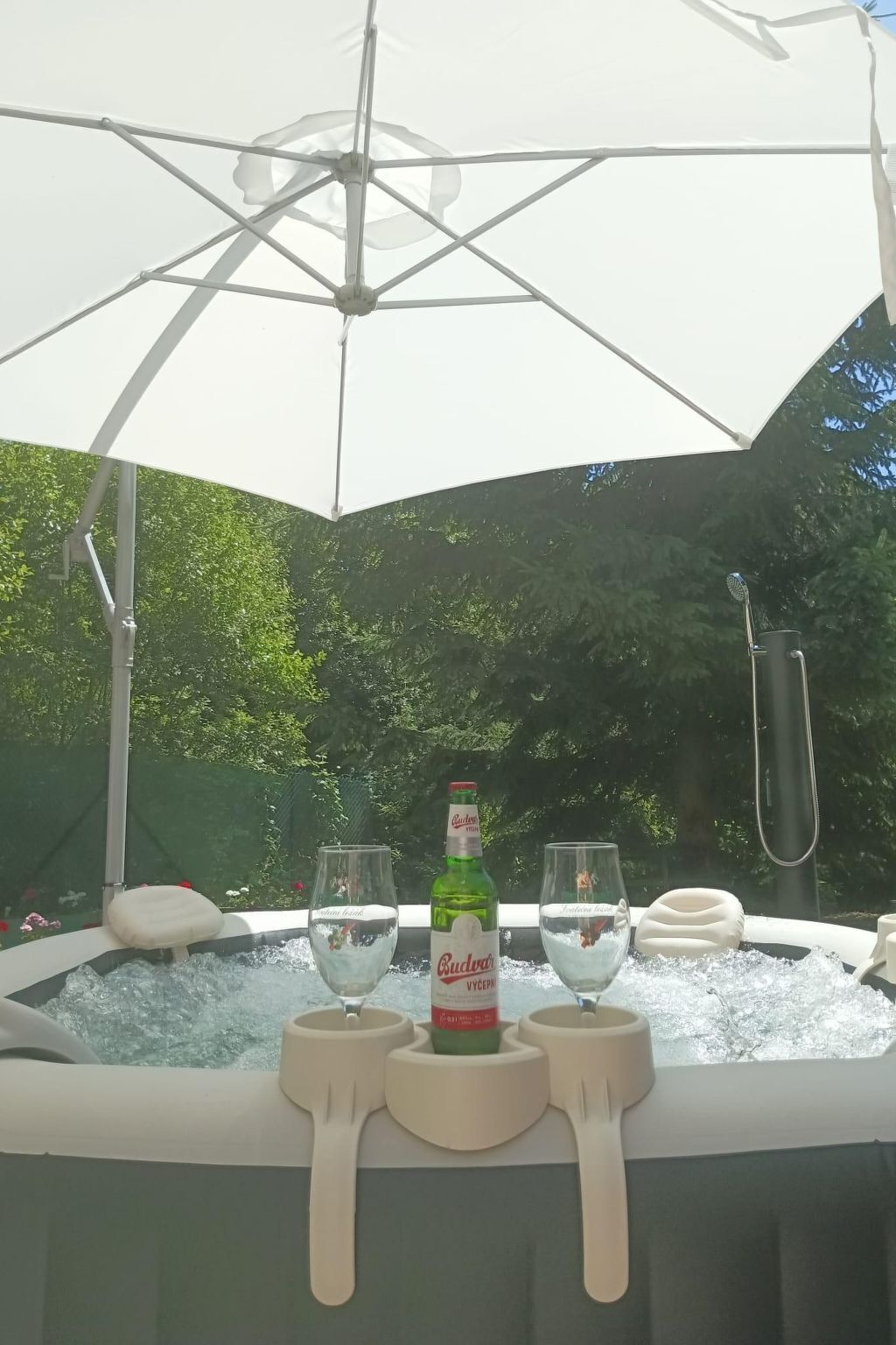 Un jacuzzi con una botella de Budweiser, dos vasos y un perchero para toallas.