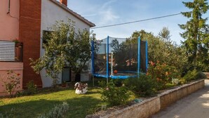 Ein Haus mit einem Ziegelkamin, einer Satellitenschüssel und einem Trampolin, das von einem blauen Sicherheitsnetz umgeben ist.
