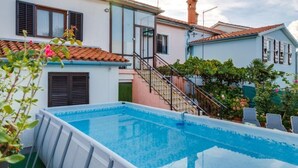 Ein Wohnpool mit einer Treppe, die zu einer zweiten Etage führt, umgeben von Häusern mit Ziegeldächern und Fensterläden.