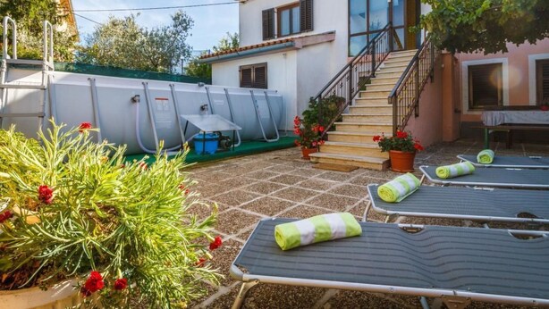 Eine Villa mit Sonnenterrasse, Schwimmbad und einer Treppe, die zu den oberen Stockwerken führt.