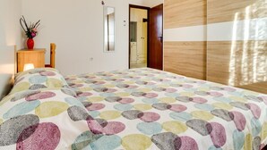 Ein Schlafzimmer mit einem Bett, einem Nachttisch mit einer Vase, einem Spiegel und einem Kleiderschrank.