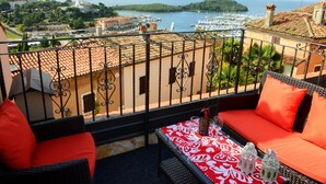 A balcony with wicker furniture, a table with a red and white tablecloth, and a view of a marina and coastal landscape. - Villa "Bella" by Interhome (Vrsar)