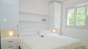 A bedroom with a bed, bedside tables, a window, and a white wardrobe. - in der Nähe des Meeres und des Sees by Interhome (Kamenmost)