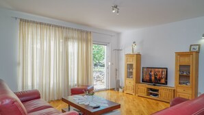 A living room with a red leather sofa, a wooden coffee table, and a television on a wooden cabinet. - in der Nähe des Meeres und des Sees by Interhome (Kamenmost)