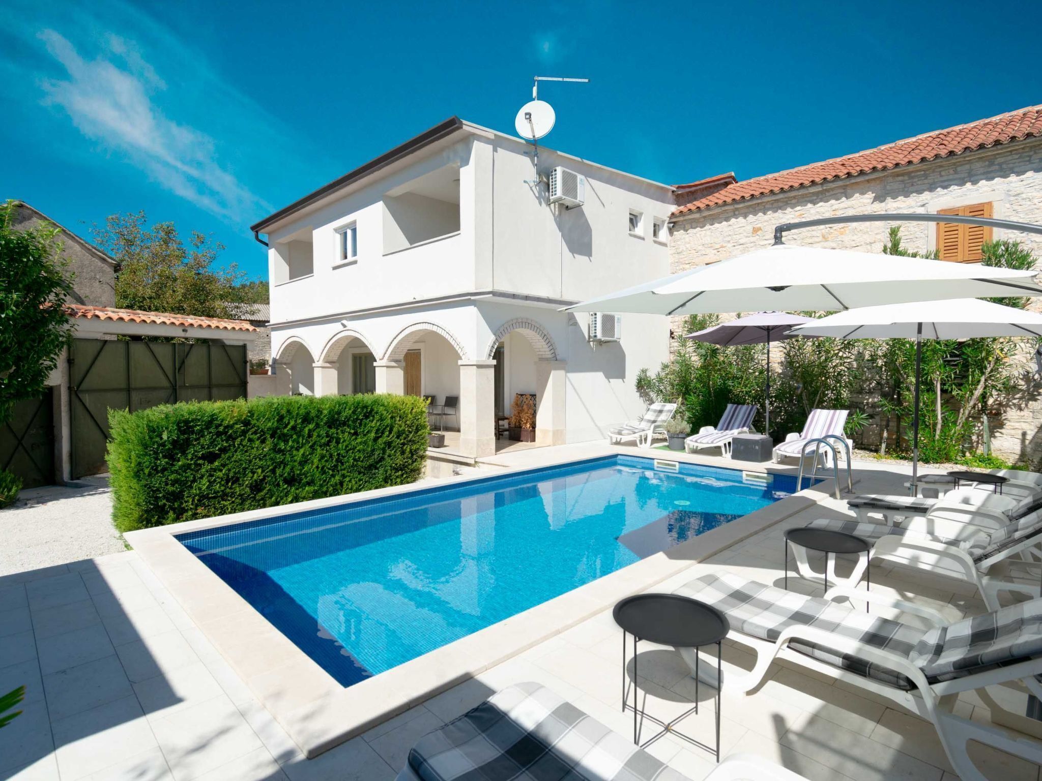 A modern villa with a swimming pool, outdoor seating, and a stone facade.