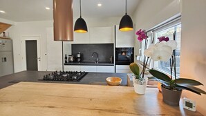 A modern kitchen with a central island, pendant lighting, and a view of the city through a window. - Ferienvilla 'Casa Doria by Interhome (Novigrad (Istra))