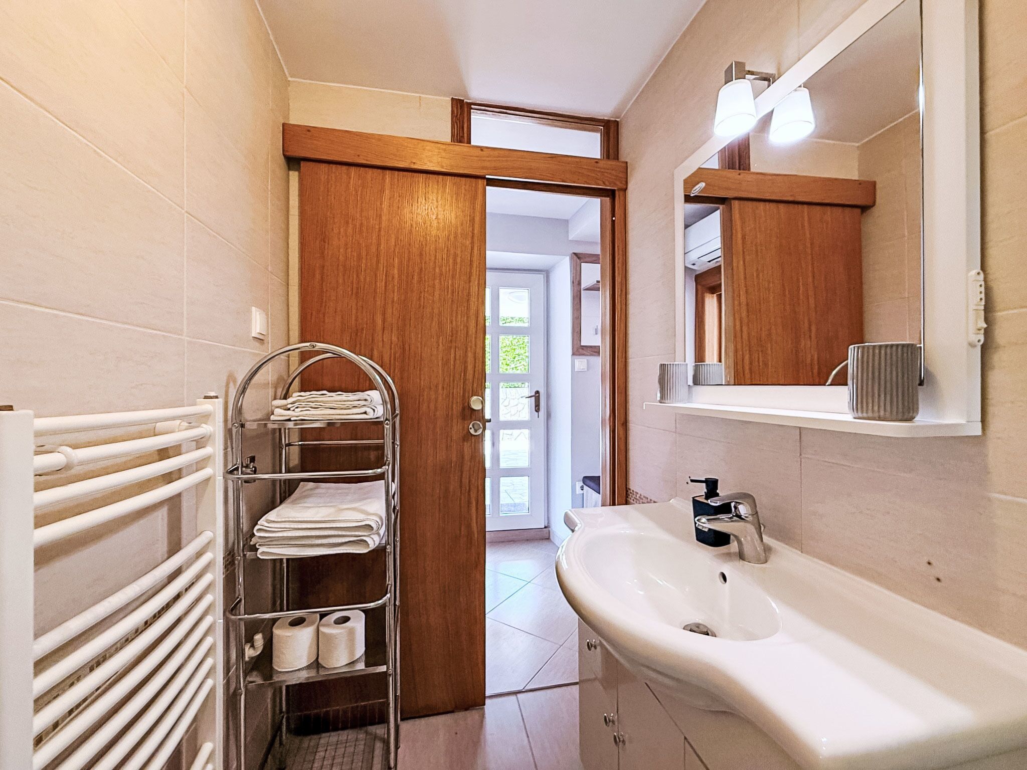 Ein Badezimmer mit Waschbecken, Spiegel, Handtuchhalter und Toilettenpapier.