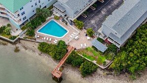 An aerial view of a hotel with a swimming pool, outdoor seating, and a beach area. - Sea Shell Pool Townhouse Across from Beach (Indian Shores)