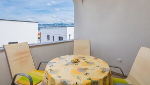 Uma varanda com mesa e cadeiras, vista para a cidade e céu claro.