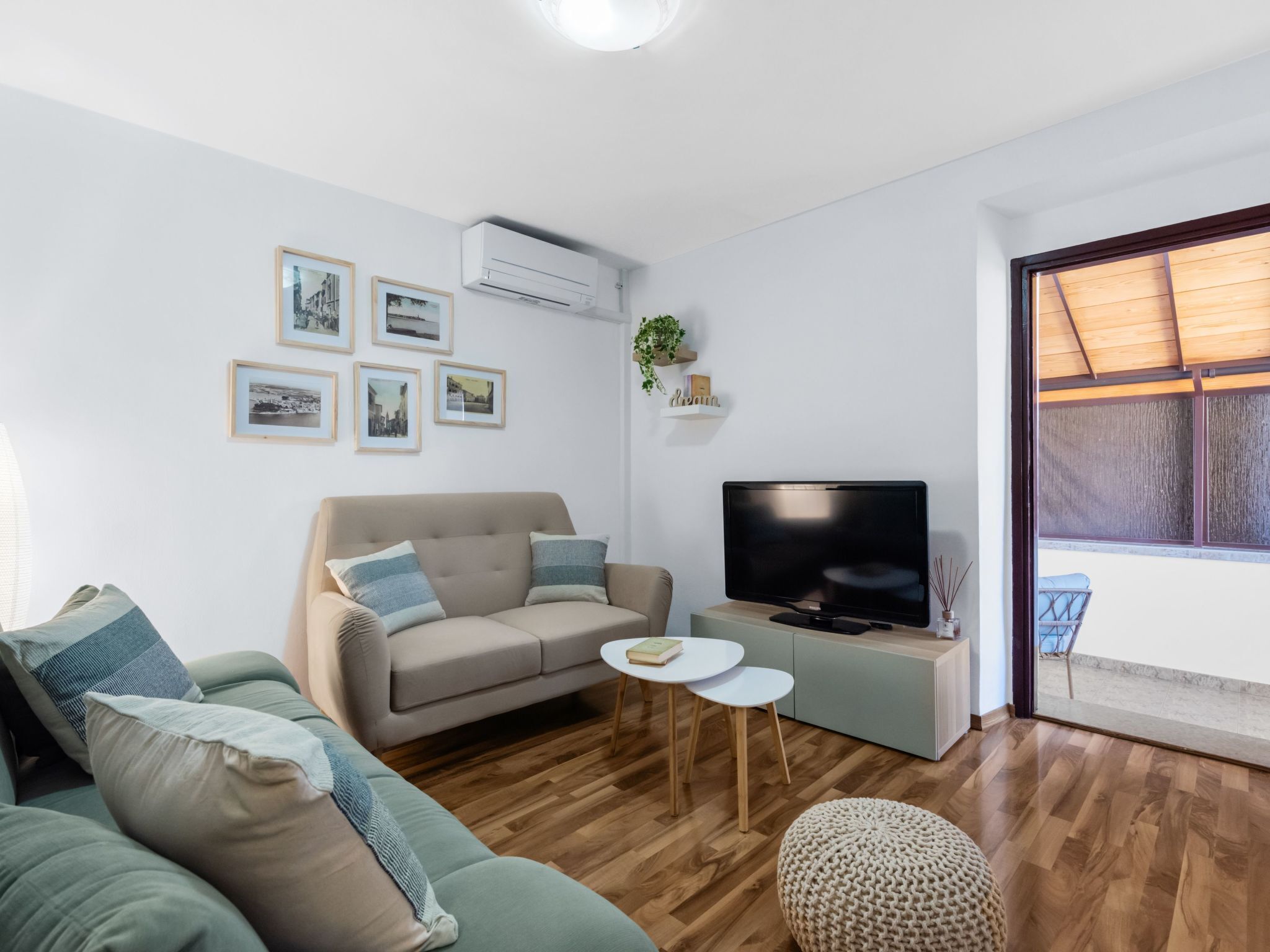 Uma sala de estar moderna com um sofá, uma mesa de centro, uma TV e quadros nas paredes.