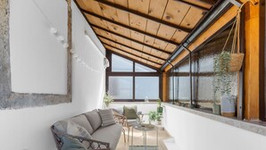 Un salon chaleureux avec un plafond en bois, un canapé, une petite table et des plantes en pot.