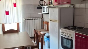 A compact kitchen with a dining area, featuring a stove, microwave, and refrigerator. - mit Kamin in der Stadt Roc by Interhome (Roč)
