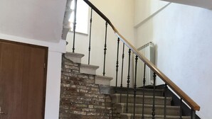 A staircase with a stone wall and metal balusters, leading to an upper floor. - mit Kamin in der Stadt Roc by Interhome (Roč)