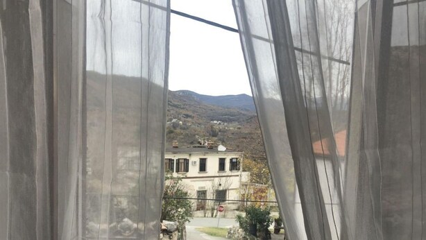 A window with sheer curtains, a view of a street, and a building in the background. - mit Kamin in der Stadt Roc by Interhome (Roč)
