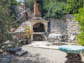 A rustic outdoor seating area with stone walls, a brick fireplace, and potted plants. - Insel Krk - Restauriertes  Steinhaus by Interhome (Krk/Čižići)