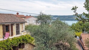 A residential area with stone walls, a stone pathway, and a view of a body of water in the distance. - Insel Krk - Restauriertes  Steinhaus by Interhome (Krk/Čižići)
