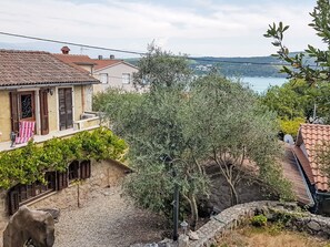 Un quartier résidentiel caractérisé par des murs en pierre, un chemin en pierre et une vue sur une étendue d’eau au loin.