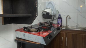 Cocina compacta con estufa a gas, un lavamanos y una pequeña encimera.