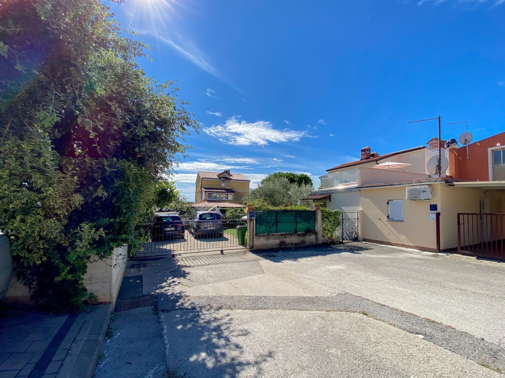 A residential street with houses, parked cars, and a clear blue sky.