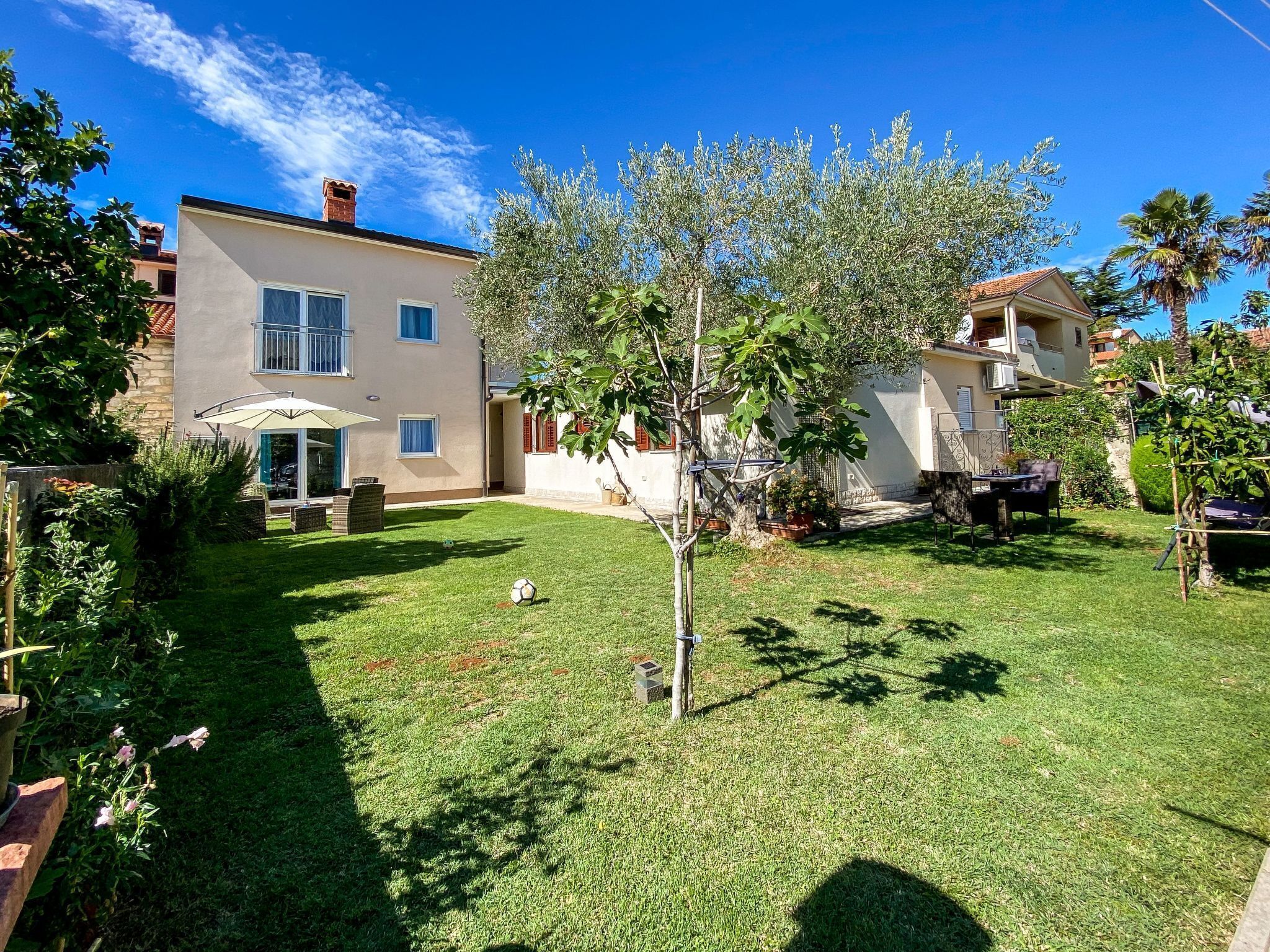 Il s’agit d’une propriété résidentielle dotée d’une pelouse bien entretenue, d’une terrasse avec mobilier d’extérieur et d’un arbre au centre.