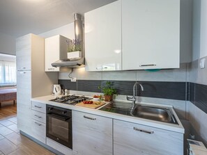 Een koelkast, een oven, een vaatwasser, kookgerei, borden en bestek