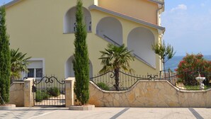 Ein zweistöckiges Gebäude mit gelber Fassade, Rundbogenfenstern und einer Steinmauer mit Tor.