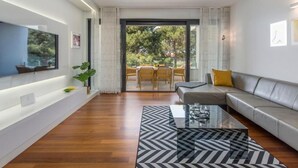 Ein modernes Wohnzimmer mit einer Couch, einem Couchtisch und einem an der Wand montierten Fernseher.