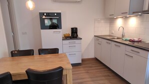 Eine moderne Küche mit Holztisch und -stühlen, einem eingebauten Backofen und einem Spülbecken.
