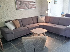 Una sala moderna con un sofá modular, una pequeña mesa de madera y un taburete acolchado.